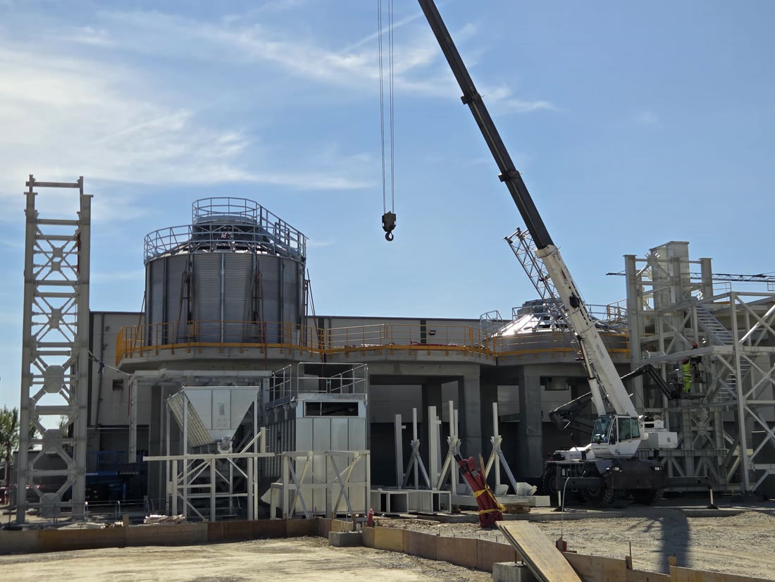 Mulmix pellet silo mounted on a raised concrete platform at the Biotim plant in Timișoara, with a telescopic crane on site